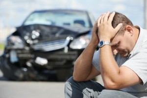 Upset man in front of a crashed car