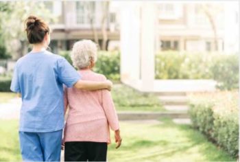 A nurse is holding a senior's shoulder in nursing home
