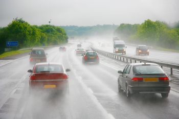Cars are driving in highway in a rainy day