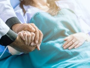 Male doctor holding female patient hand on the hospital bed