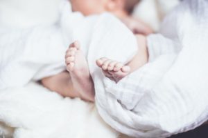 A new born baby is wrapped by white cloth