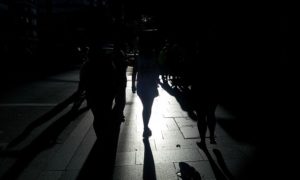 People are walking on street with dim lights