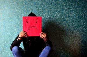 Man holds an unhappy expression covering his face